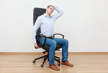 Caucasian man, sitting on office chair, stretching neck