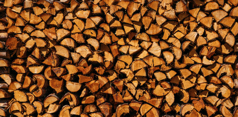 Wall of stacked wood logs as background. Wood pile for fireside. Dry oak firewood stacked in a pile Natural wood background.
