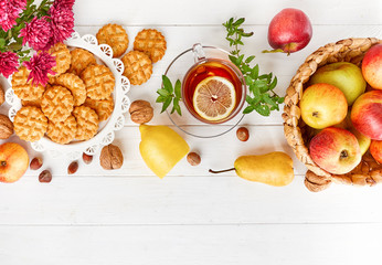 Tea with herbs fruits and cookies. Still life with hot drink apple and nuts at white wooden board in rustic style.