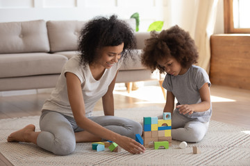 Happy biracial mom and daughter play with building bricks