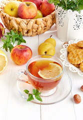 Tea with herbs fruits and cookies. Still life with hot drink apple and nuts at white wooden board in rustic style.