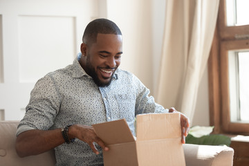 Happy biracial man feel excited unpacking delivery package