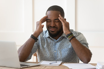 Unwell african American male massage temples suffering from headache