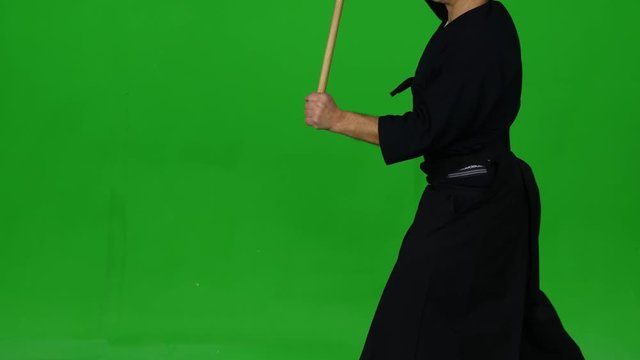 Masculine Kendo warrior practicing martial art with the bamboo bokken on green screen. CLose up
