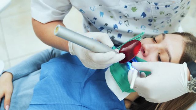 The girl in the office at the dentist. Dental restoration and material polymerization with UV light.