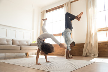 Active biracial dad and daughter exercise at home together