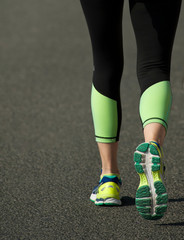 Fototapeta na wymiar asphalt runner with black pants and green right foot in motion