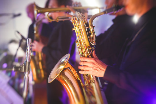 Concert view of a saxophone player with vocalist and musical jazz band in the background