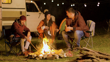 Bearded man telling a funny joke to his friends around camp fire