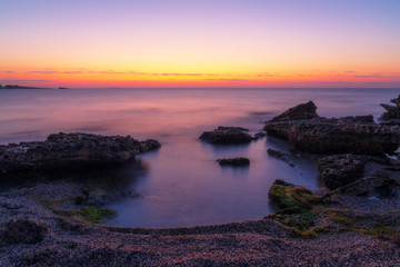 Fototapeta na wymiar Colorful dawn on a rocky seashore, long exposure photography