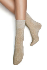 Cropped shot of a girl's foots, lying on a white background. It is beige socks on her foots. 
