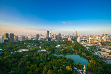 Sightseeing scence of Lumpini park around modern office buildings and condominium in downtown of Bangkok city  with sunset sky clouds