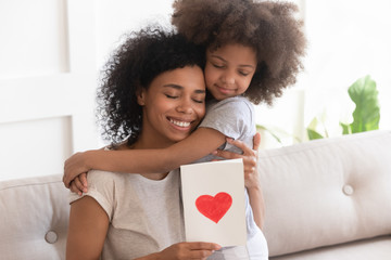 Little biracial girl hug greeting mom with postcard