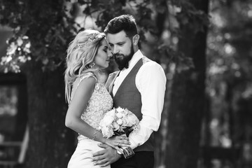 Sensual Black and white foto of bride and groom. Stylish couple of happy newlyweds posing and kisses in the park on their wedding day. Together. The concept of youth, love, fashion and lifestyle. 