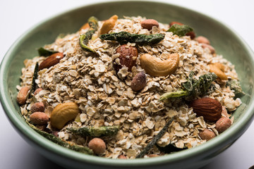 Oats Chivda / Chiwda is a healthy indian recipe with added chilli, peanuts, cashew, almond and curry leaf for flavour. Selective focus