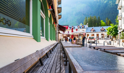 Cozy street with tables of cafe old town street in Chamonix village, France. Architecture and landmark. Cozy cityscape. Typical view of the street with tables of cafe in Chamonix.