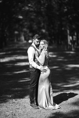 Fototapeta na wymiar Sensual Black and white foto of bride and groom. Stylish couple of happy newlyweds posing and kisses in the park on their wedding day. Together. The concept of youth, love, fashion and lifestyle. 