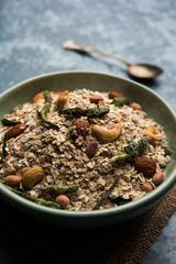 Oats Chivda / Chiwda is a healthy indian recipe with added chilli, peanuts, cashew, almond and curry leaf for flavour. Selective focus