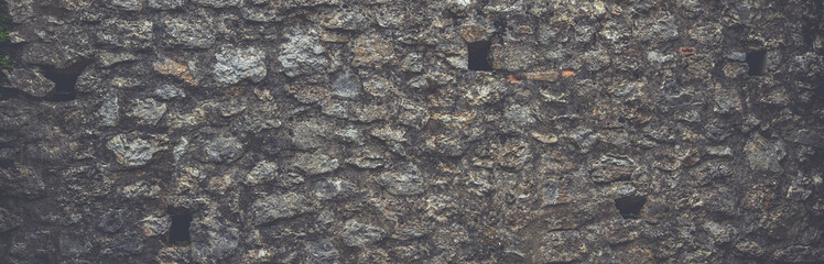 Pattern gray and brown color of retro style design decorative uneven cracked real stone wall surface medieval town.