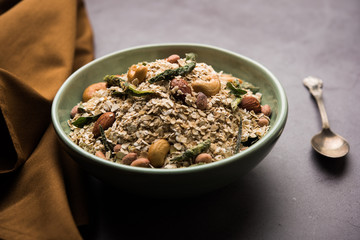 Oats Chivda / Chiwda is a healthy indian recipe with added chilli, peanuts, cashew, almond and curry leaf for flavour. Selective focus