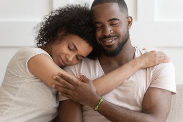 Happy African American couple cuddle hugging at home