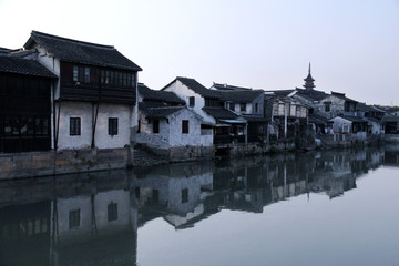 Fototapeta na wymiar The ancient houses in Jiangsu, China, the white walls and black corrugated are scattered next to the canal. In the early morning, the light of the river reflects the ancient scenery of the river.