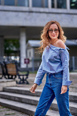 Fototapeta premium Young beautiful woman with long brown hair in sunglasses on a walk on a cloudy day.