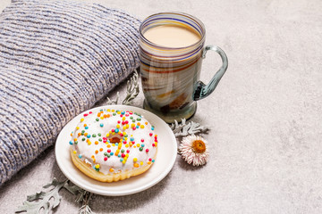 Hot coffee with a donut. Winter drink for a good mood with sweater, leaves and flowers. Old wood plank background
