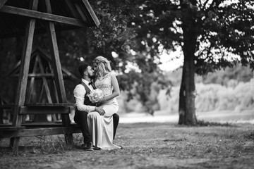 Sensual Black and white foto of bride and groom. Stylish couple of happy newlyweds posing and kisses in the park on their wedding day. Together. The concept of youth, love, fashion and lifestyle. 