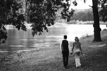 Sensual Black and white foto of bride and groom. Stylish couple of happy newlyweds posing and kisses in the park on their wedding day. Together. The concept of youth, love, fashion and lifestyle. 