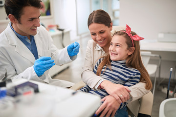 Family in dentist’s office.dentist examining his girl patient in dentist’s clinic