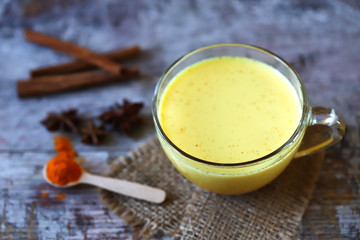 Turmeric milk with spices in a mug. Golden turmeric milk. Indian health drink. Selective focus. Macro.