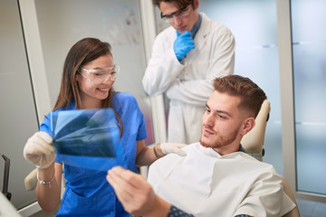 Fototapeta na wymiar .Smiling Doctor dentist showing patient's teeth on X-ray