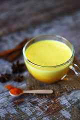 Turmeric milk with spices in a mug. Golden turmeric milk. Indian health drink. Selective focus. Macro.