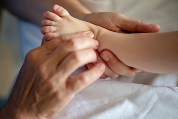 Baby having foot massage in a rehabilitation center. Little child on therapy. Massage therapist massaging a baby.