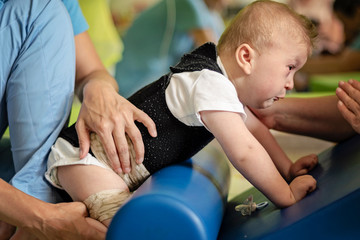 Portrait of a baby with cerebral palsy on physiotherapy in a children therapy center. Boy with...