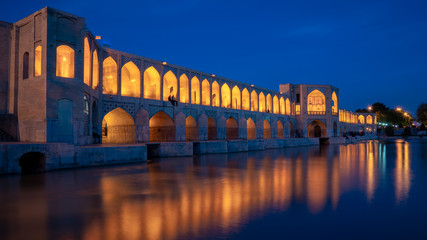 Khaju-Brücke über den Fluss Zayandeh in der Abenddämmerung mit Lichtern während der blauen Stunde, Isfahan, Iran