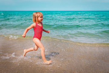 cute little girl run and play with waves on the beach
