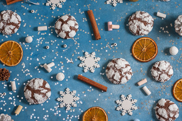 Obraz na płótnie Canvas Christmas and New Year pattern made of snowflakes,cookies, cinnamon, orange, cones and marshmallows on a blue background with stars. Christmas, winter, new year concept. Flat lay, top view, copy space