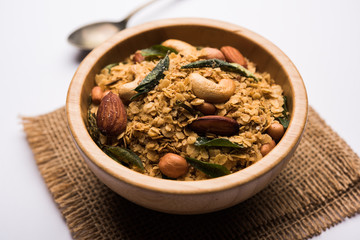 Oats Chivda / Chiwda is a healthy indian recipe with added chilli, peanuts, cashew, almond and curry leaf for flavour. Selective focus