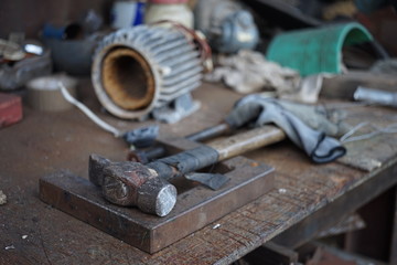 Old hammer with a wooden handle wrapped in electrical tape on a joiner's desk. Garage Tools