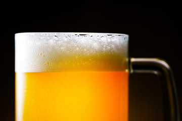Light Beer Mug with White Foam on Dark Background Close Up