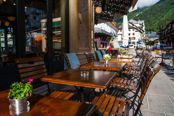 Cozy street with tables of cafe old town street in Chamonix village, France. Architecture and landmark. Cozy cityscape. Typical view of the street with tables of cafe in Chamonix.