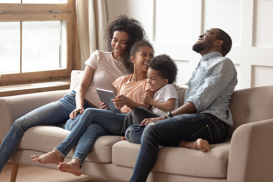 Cheerful mixed-race family with kids using tablet computer