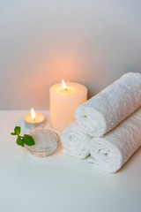 Obraz na płótnie Canvas SPA treatment procedure photo with stack of towels, sea salt in a cup and candles, vertical orientation.
