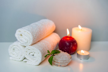 Natural health treatments of SPA. White towels, sea salt in a cup, candles.