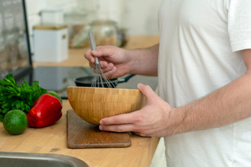 The hands of a man cook prepare a dressing for a vegetarian salad in the kitchen of the house.