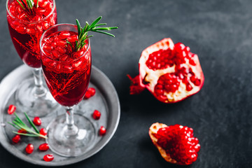 Pomegranate Champagne Cocktail with rosemary on gray concrete stone background