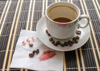 Empty cup of coffee with lipstick prints of a woman. Kiss the track on a napkin with a phone number.
