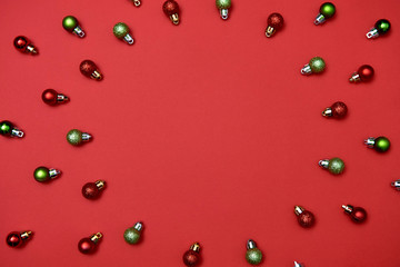 Creative Christmas pattern with red and green shiny baubles on red background, copy space. Minimal, winter, new year concept. Top view, flat lay